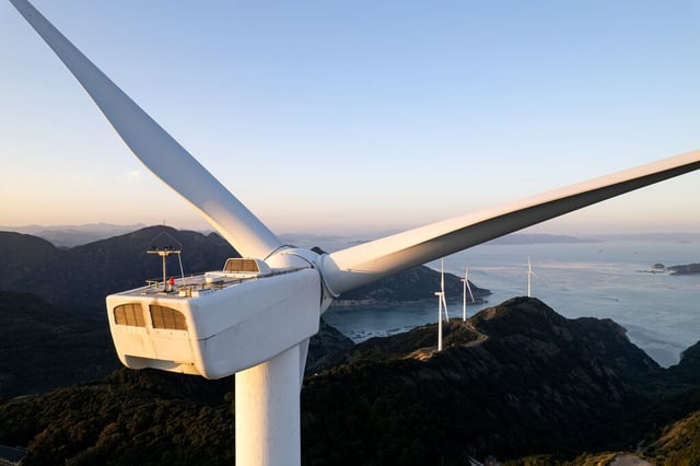 Aerogeneradores en colinas costeras que generan energía renovable, representando soluciones sostenibles para la energía y el clima.