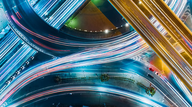 Vista aérea de una red vial con flujos de luz en movimiento, representando cómo LRQA ayuda a ampliar el valor ofrecido a los clientes mediante conectividad, agilidad y soluciones integradas.